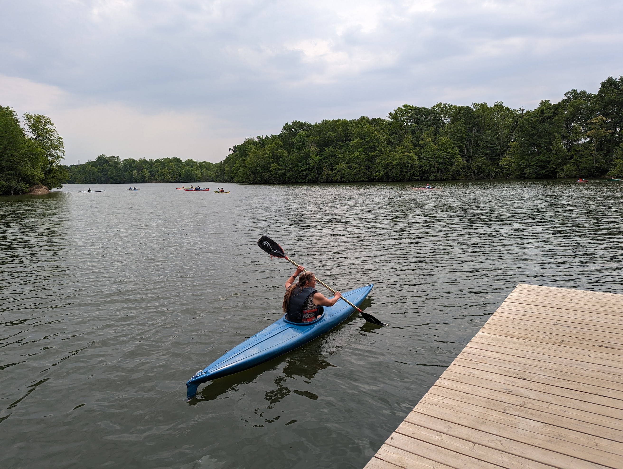 A canoe club member paddling a blue kayak