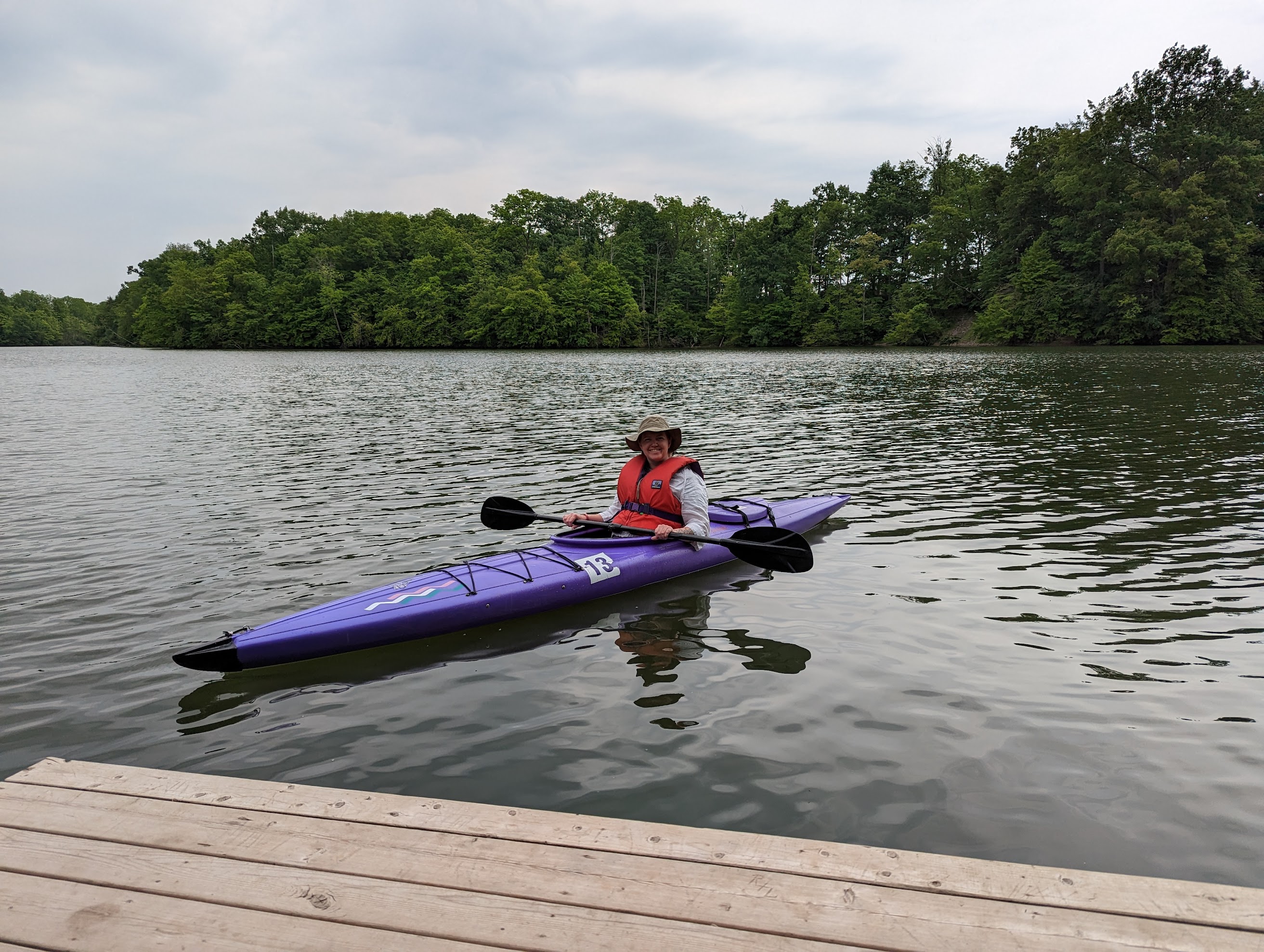 A canoe club member paddling a purple kayak